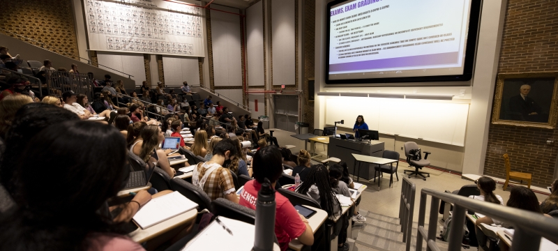 photo of lecture hall with students, screens