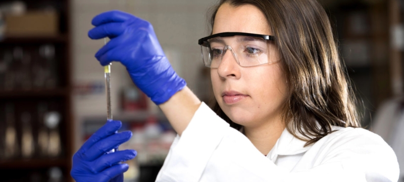 photo of woman with testable, blue gloves, lab coat