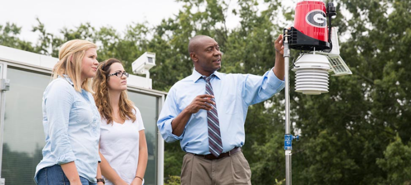 photo of man with students outdoors with rain gauge