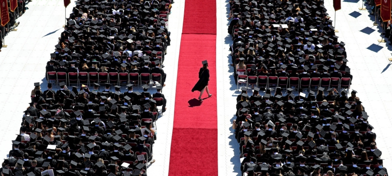 photo of student walking across red carpet at commencement