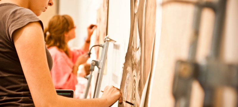 photo of people drawing on paper attached to a wall