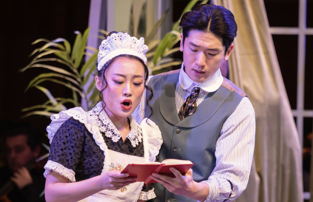 photo of man and woman holding book, woman singing