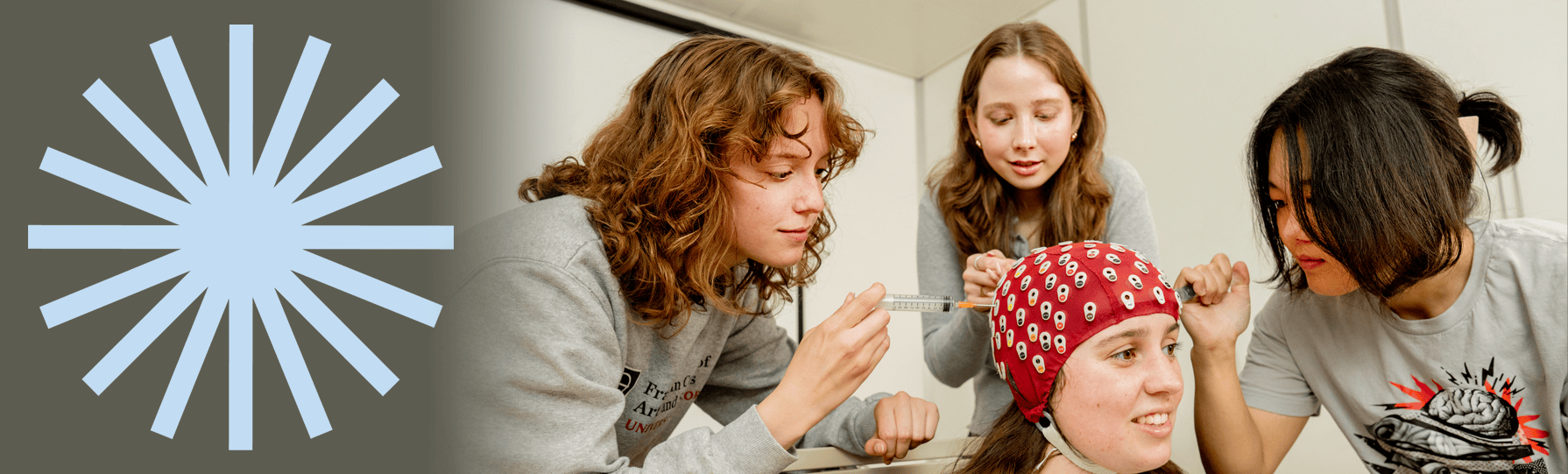 Student wearing a red head cover with students injecting things into it