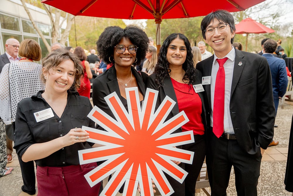 Four students smiling at the camera with a Franklin spark logo over the photo