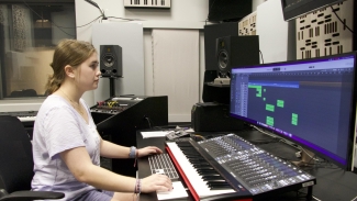 photo of student sitting at sound board with computer screen