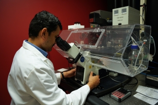 photo of man using microscope in lab