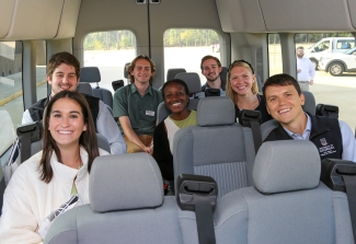 photo off seven smiling students inside a van