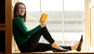 photo of woman with book in window sill