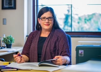 photo of woman in office with book and pen
