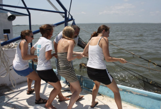 photo of four women pulling rope line on boat