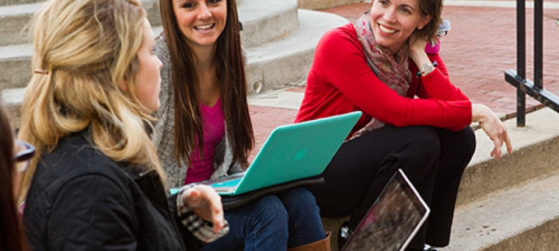 girls on steps, with laptops smiling