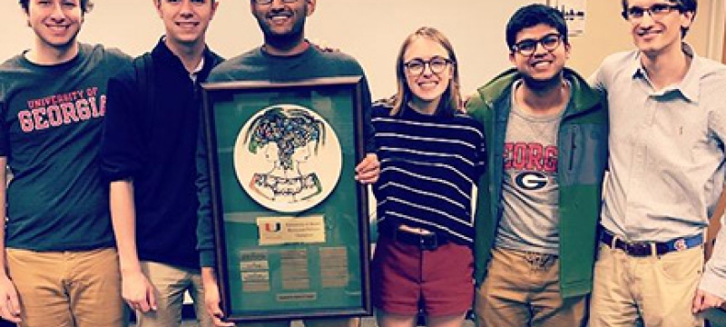 photo of five students with plaque 