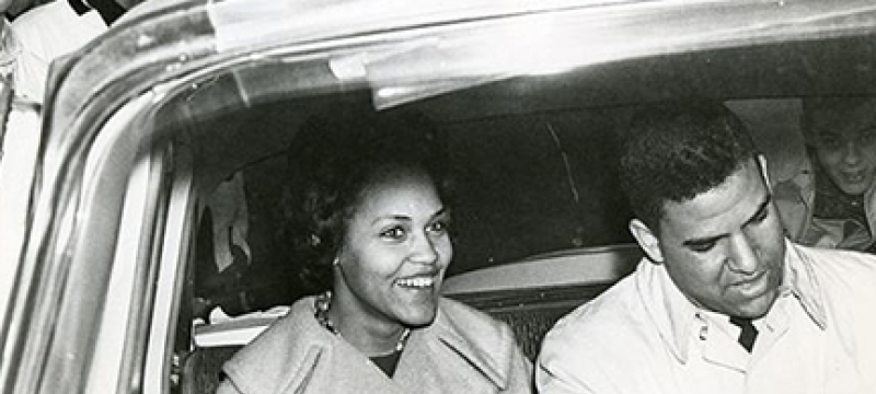 b/w photo of two people in a car, from outside