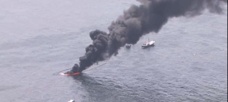 aerial photo of black smoke rising from the ocean water