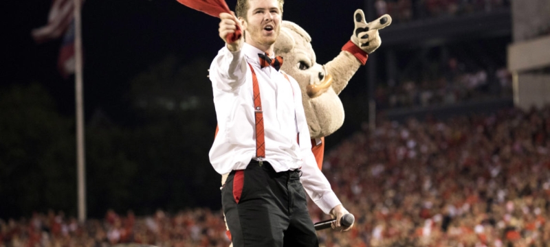 man at football game with mascot, crowd