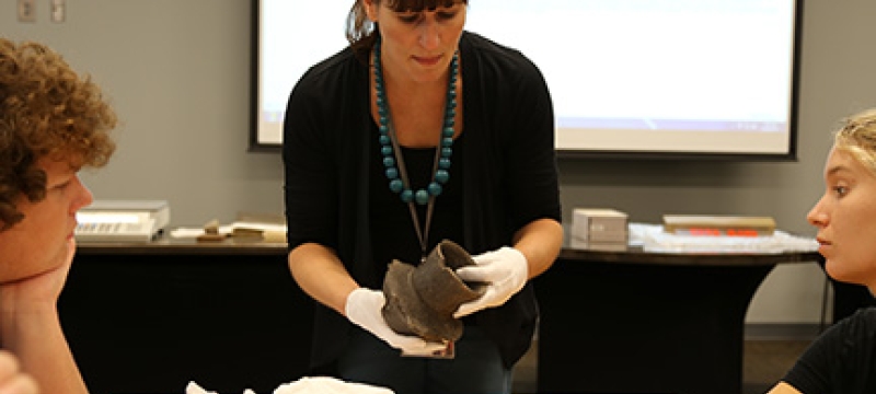 professor with artifact, students