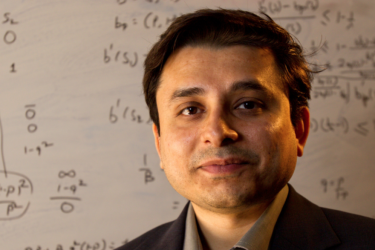 Environmental portrait of Creative Research Medal winner Prashant Doshi with mathematical equations on white board in background