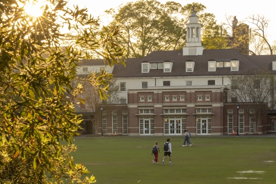 photo of students on quad near sunset, building in background