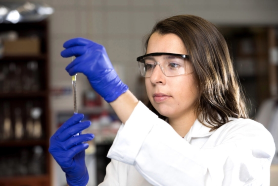 photo of woman with testable, blue gloves, lab coat