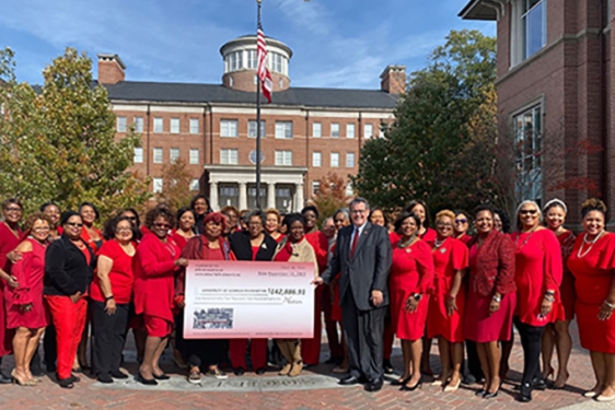 group photo of women wearing red, outdoors, with blue sky and large check