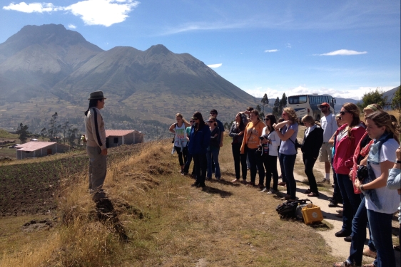 photo. of students with instructor, mountains and village in background