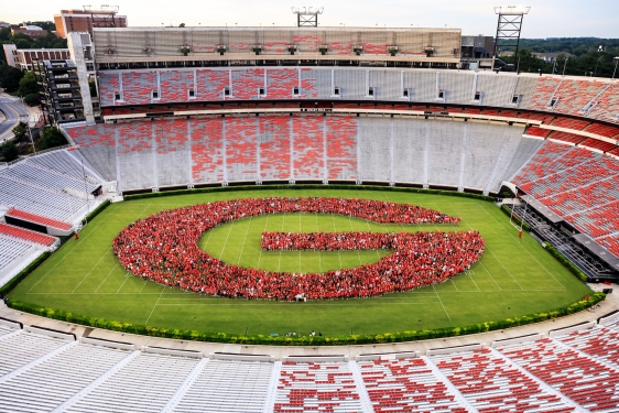 photo of large group of people forming G in stadium