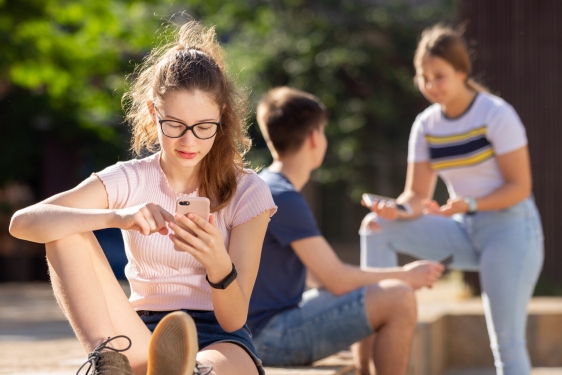 young people outside on their phones