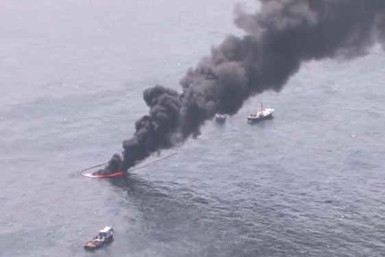aerial photo of black smoke rising from the ocean water