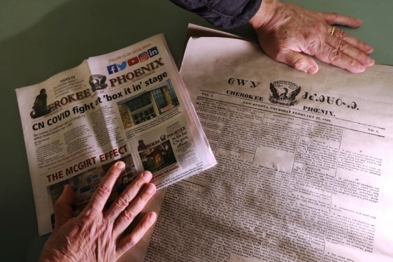 photo of hands and two newspapers in different languages