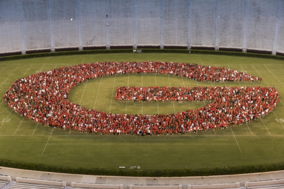 photo of people forming the letter G on a stadium grass field