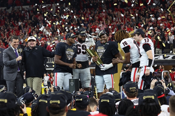 photo of football players on stage, with confetti and trophy