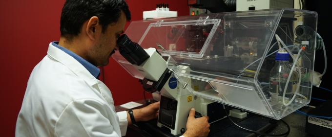 photo of man using microscope in lab