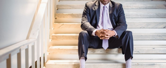 photo of man sitting on stairs in suit.