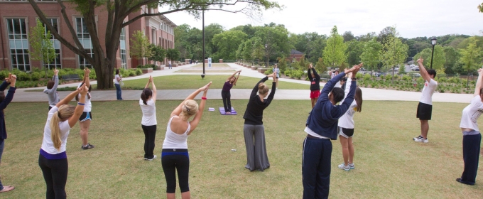 photo of group of people stretching with arms overhead, outdoors