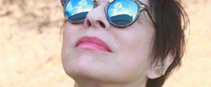 photo of woman looking up, with sunglasses reflecting sky
