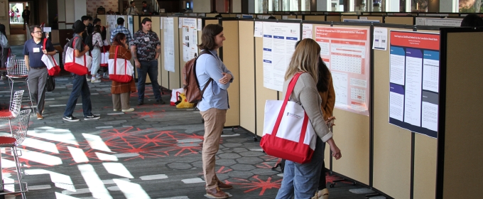 photo of people looking at research posters, indoors