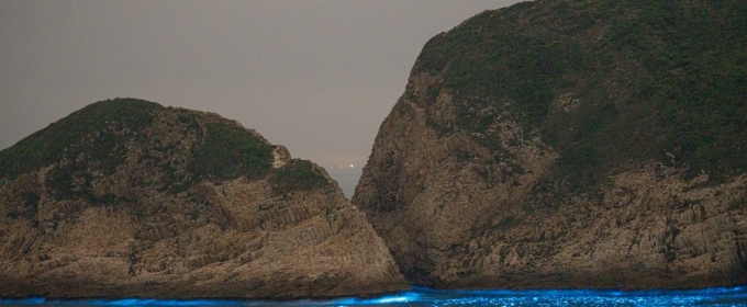 photo of land and sea with light blue shoreline